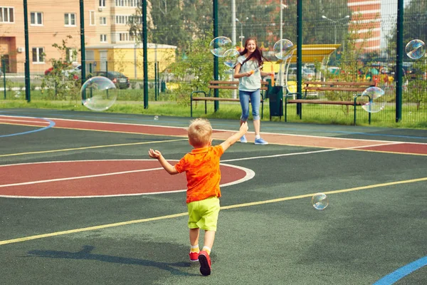 Niño con madre jugando con soplador de burbujas —  Fotos de Stock