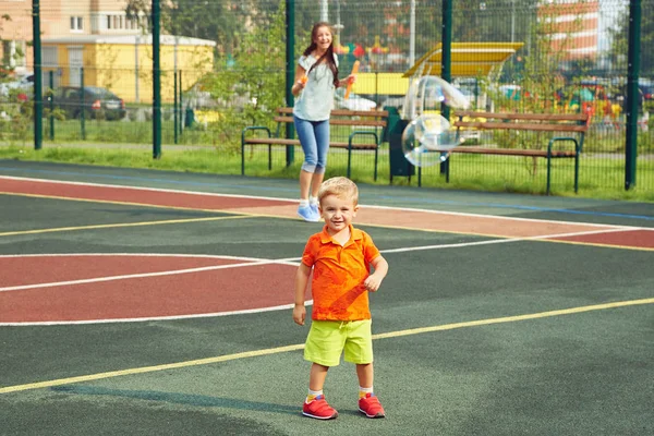 Barn med mamma leker med bubble blower — Stockfoto