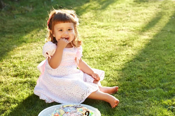 Outdoor Portret van een meisje. kind eten taart op het gras — Stockfoto