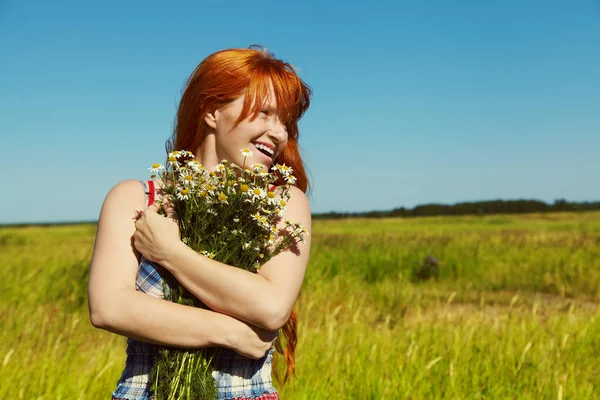 Roodharige vrouw met een boeket van bloemen in een jurk buiten. stijlvolle, romantische jong meisje in veld — Stockfoto