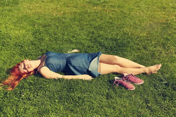 Kızıl saçlı kız çim üzerinde yalan rahatlatıcı. kadın gevşeme açık — Stok fotoğraf