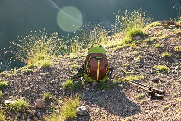 trekking backpack and hiking poles on mountain road