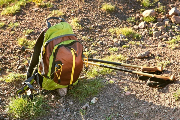 Trekking backpack and hiking poles on mountain road — Stock Photo, Image