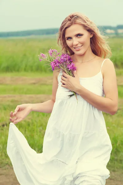 Außenporträt einer blonden Frau mittleren Alters. attraktive sexy Mädchen in einem Feld mit Blumen — Stockfoto