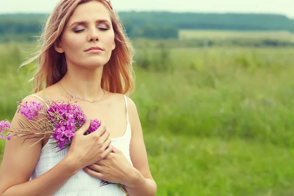 Außenporträt einer blonden Frau mittleren Alters. attraktive sexy Mädchen in einem Feld mit Blumen — Stockfoto