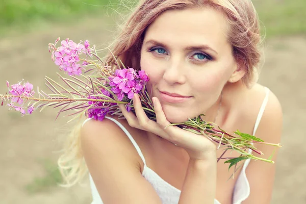 Retrato al aire libre de una mujer rubia de mediana edad. atractiva chica sexy en un campo con flores —  Fotos de Stock