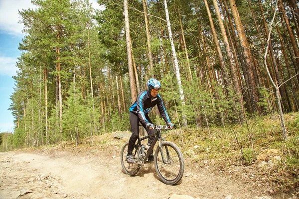 Ciclista montando uma bicicleta de montanha ao longo da estrada da floresta — Fotografia de Stock
