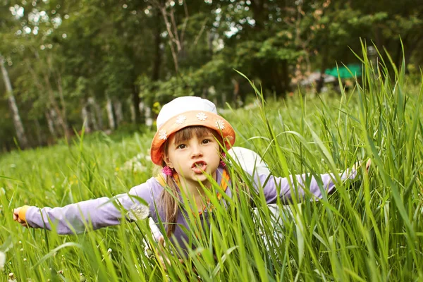 Kleines fröhliches Mädchen, das im Gras spielt, stellt ein Flugzeug dar — Stockfoto