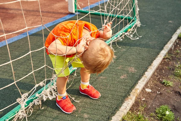 フットボールゲートのグリッドを持つ遊び場の小さな男の子 — ストック写真