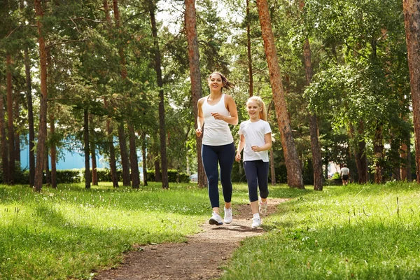 Running moeder en dochter. vrouw en kind joggen in een park. buitensporten en fitness familie — Stockfoto