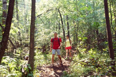 Ormanda gezen genç çiftler. Sırt çantalı kadın ve erkek sporcular