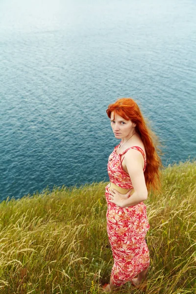 Romantique rousse jeune femme dans une robe sur la côte de la mer — Photo