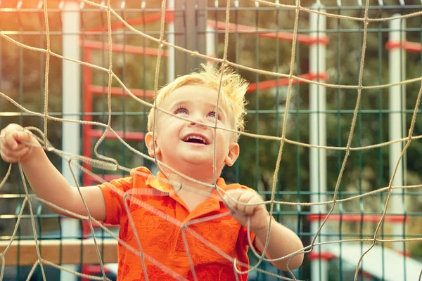 Funny little boy on playground with a grid of football gate — Stock Photo, Image