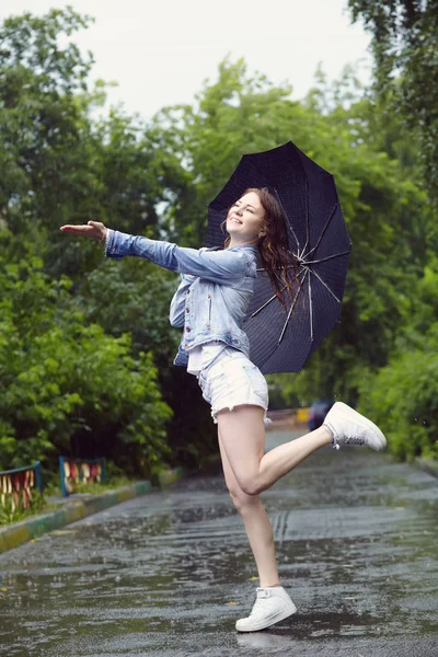 Donna allegra con un ombrello che cammina sotto la pioggia — Foto Stock