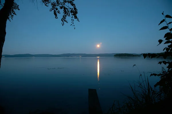 Reflection of the full moon in a lake water. Night landscape