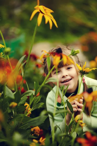 Schattig klein meisje in de tuin met bloemen — Stockfoto