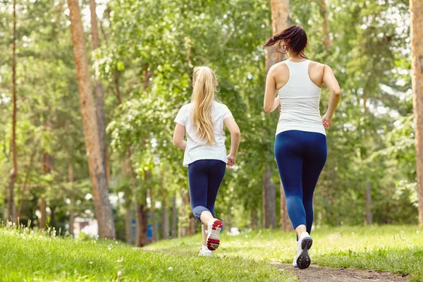 V provozu sportovní matky a dcery. Žena a dítě běhají v parku. venkovní sporty a fitness rodina — Stock fotografie