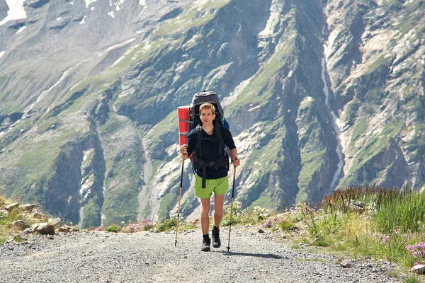 Escalador en el camino en las montañas. un hombre con una mochila en una caminata —  Fotos de Stock