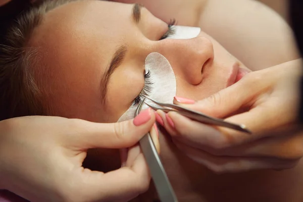 beautician making artificial lashes. eyelash extension procedure.