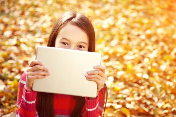 Portret van een tiener meisje met Tablet computer in de herfst buiten. — Stockfoto