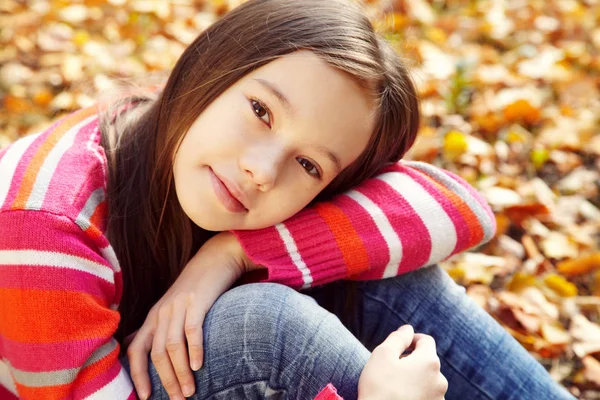 Portret van een mooi lachende tiener meisje met gele bladeren in de herfst — Stockfoto