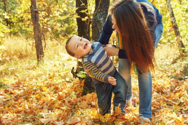 yürüyüş ve bebeği ile genç anne oynarken açık havada. Anne ve oğlu bir sonbahar parkında