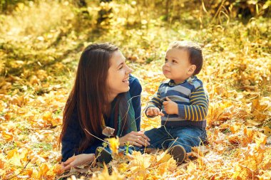 yürüyüş ve bebeği ile genç anne oynarken açık havada. Anne ve oğlu bir sonbahar parkında