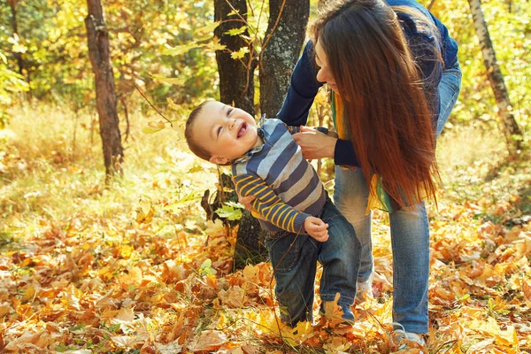 Camminare e giocare giovane madre con il suo bambino all'aperto. Mamma e figlio in un parco autunnale — Foto Stock