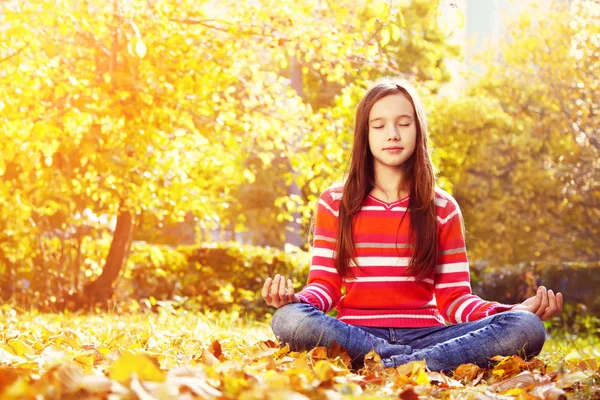 Teenage girl meditating in the autumn park — Stock Photo, Image