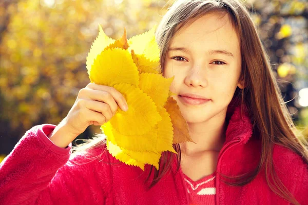 Retrato de cerca de una hermosa adolescente sonriente con hojas amarillas en otoño . —  Fotos de Stock