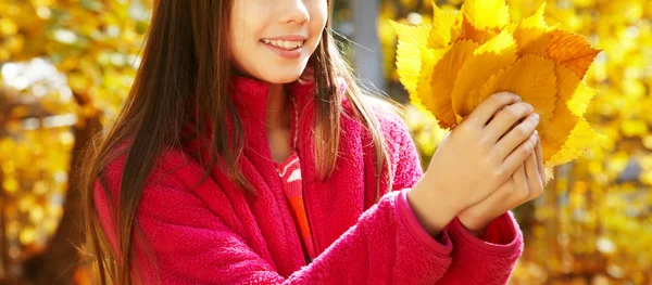 Närbild vacker leende tonårs flicka med gula löv i höst. — Stockfoto