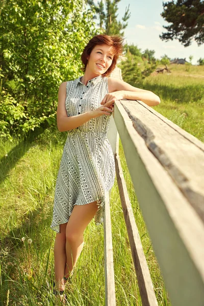 Verão relaxar retrato rústico de uma jovem mulher perto de cerca no campo . — Fotografia de Stock