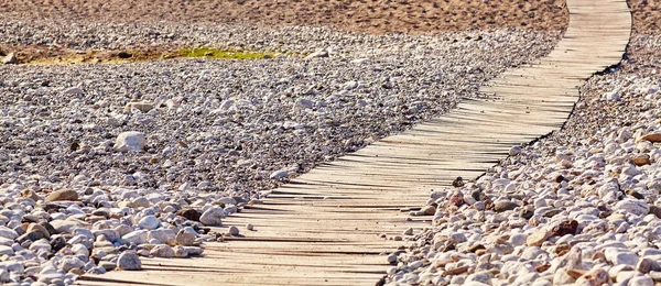 Dřevěná promenáda na tropické pláži oblázkové. — Stock fotografie