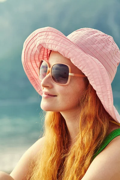 Portret van een mooie jonge ontspannende vrouw met hoed en zonnebril. een meisje op het strand aan zee. — Stockfoto