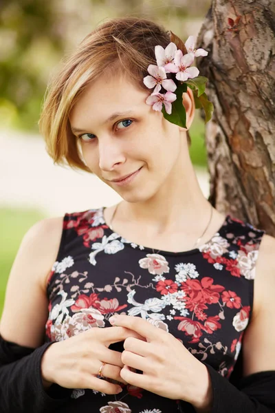 Bela jovem sorridente com flores de primavera em seu cabelo . — Fotografia de Stock