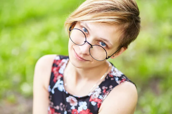 Retrato de uma bela jovem sorridente em óculos em um parque . — Fotografia de Stock
