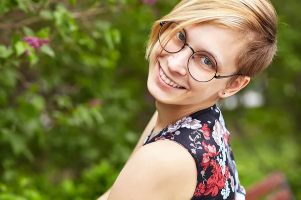 Portrait d'une belle jeune femme souriante dans des lunettes dans un parc . — Photo