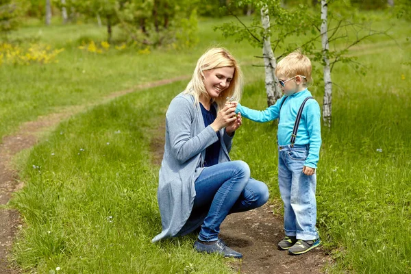 Sonen ger blommor till sin mor. barn och mamma går. — Stockfoto