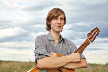 Akustik gitarlı yakışıklı genç bir adam..