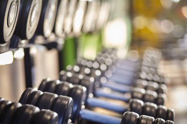 Spor salonunun arka planındaki spor salonunda sıra sıra duran halterler..