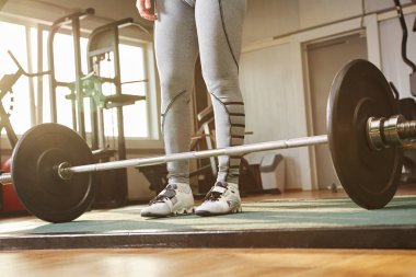 Spor salonunda halterle antrenman yapan bir kadının yakın plan bacakları..