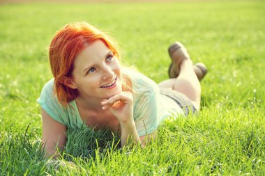 Genç rahatlatıcı Kızıl saçlı kız çim üzerinde yalan. kadın gevşeme açık.