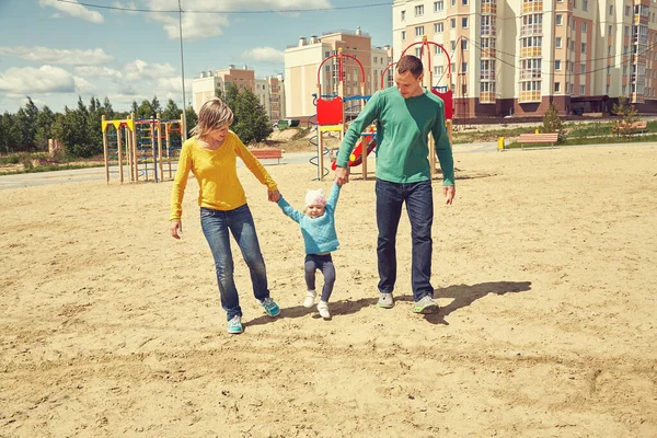 Gelukkig spelen familie buiten. Jonge ouders met een baby die in de zomer loopt. Moeder, vader en kind. — Stockfoto