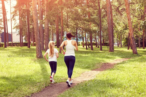 Running sporty mother and daughter. woman and child jogging in a park. outdoor sports and fitness family. — Stock Photo, Image