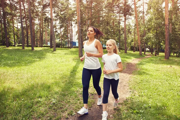 Sportieve moeder en dochter. vrouw en kind joggen in een park. outdoor sport en fitness familie. — Stockfoto