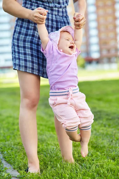 Mor lär sitt barn att ta de första stegen barfota på gräset. — Stockfoto