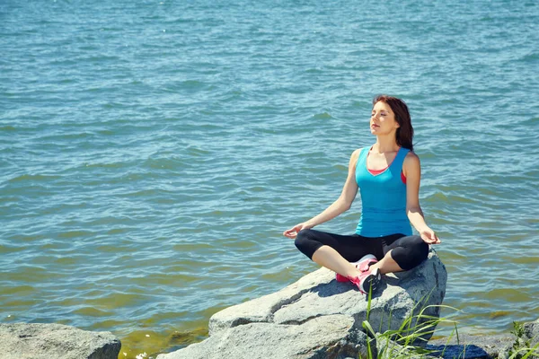 Genç ve güzel bir kadın deniz kıyısında meditasyon yapıyor.. — Stok fotoğraf