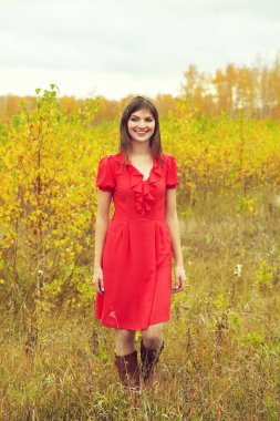 Güzel, esmer, orta yaşlı, kırmızı elbiseli bir kadının sonbahar portresi.