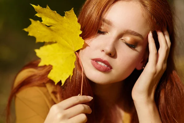 Женщина с желтыми кленовыми листьями осенью — стоковое фото