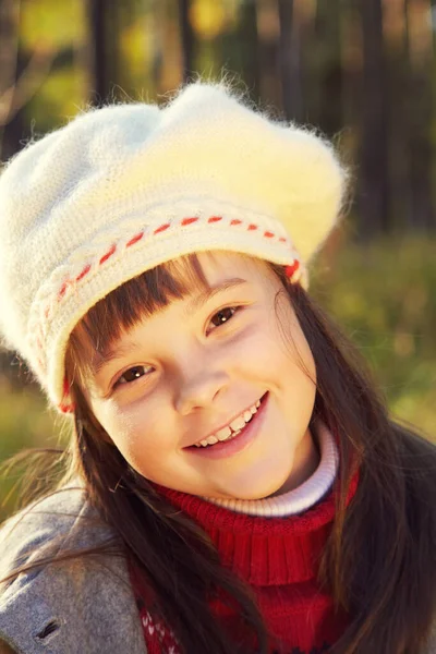 Nahaufnahme Porträt eines niedlichen lächelnden kleinen Mädchens in Mantel und Baskenmütze im Herbst. — Stockfoto
